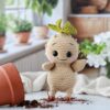 Crochet Creatures A crocheted root sprout escaping his pot with a bright kitchen with plants in the window in the background.
