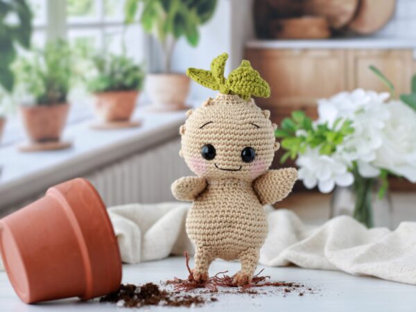 Crochet Creatures A crocheted root sprout escaping his pot with a bright kitchen with plants in the window in the background.