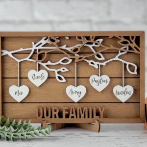 3 Layer Mahogany Wood Frame with tree branches with dangling hearts that have family first names on them. Our Family is laser cut out of the open top frame.